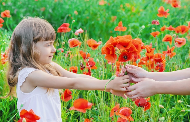 Kindermädchen auf einem Gebiet mit Mohnblumen.