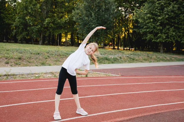 Foto kindermädchen beim aufwärmtraining im freien vor dem laufen