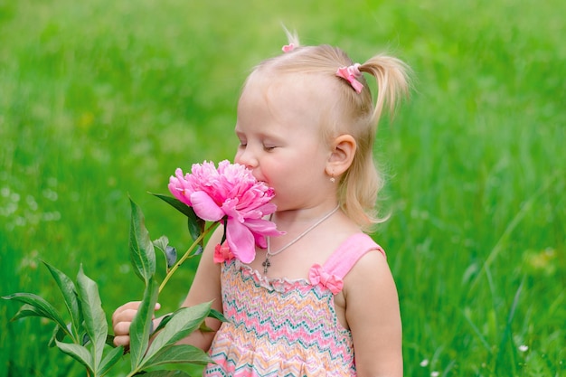 Kindermädchen, das an einer Pfingstrosenblume schnüffelt