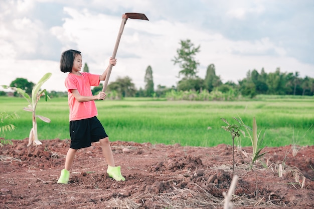 Kindermädchen, das Hacke hält und Erde zum Pflanzen von Bäumen im Garten gräbt