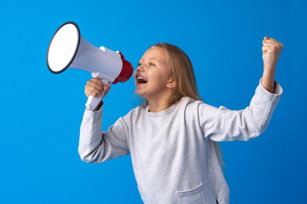 Kindermädchen, das Megaphon gegen blauen Hintergrund verwendet