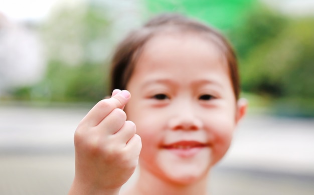 Kindermädchen, das Miniherzzeichen durch Daumen und Zeigefinger für ich liebe dich macht.