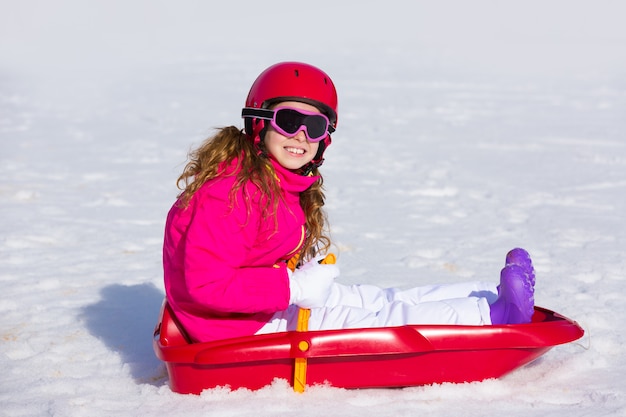 Kindermädchen, das Schlitten im Winterschnee spielt