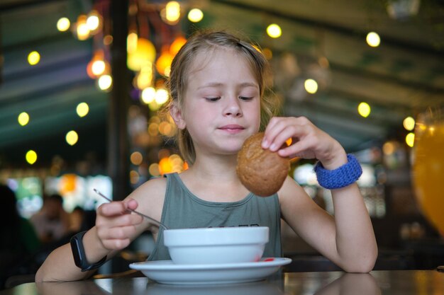 Kindermädchen, das Suppe und leckeren Burger im Restaurant isst.