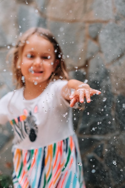 Kindermädchen, das Wasser am Sommertag spritzt