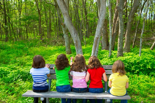 Kindermädchen, die auf der Parkbank betrachtet Wald sitzen