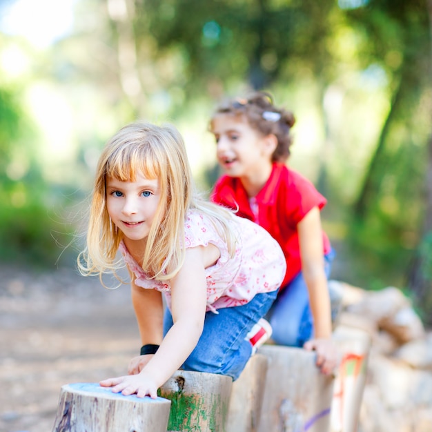 Kindermädchen, die auf stämmen in der waldnatur spielen