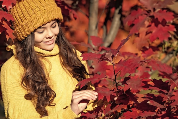 Kindermädchen im Herbstpark im Freien scherzt Spaßgesicht lächelndes jugendlich Mädchen im Hut am Herbstlaub auf natürlichem Hintergrund