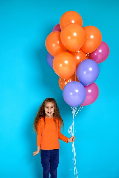 Kindermädchen im rosafarbenen T-Shirt, das mit hellen bunten Luftballons aufwirft