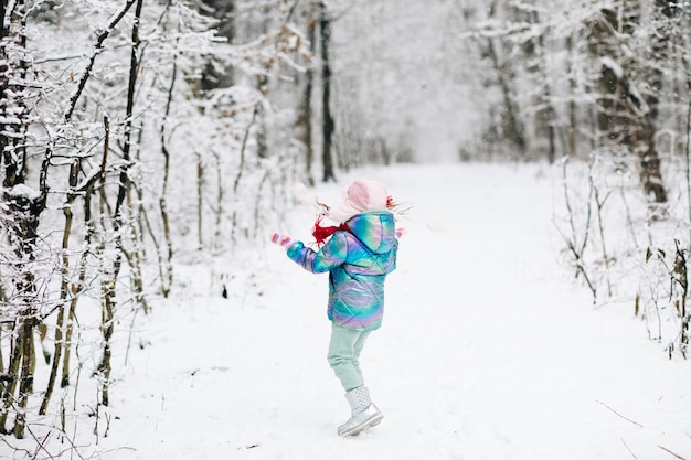 Kindermädchen im Winter, das im Schnee in Park im Freien spielt.