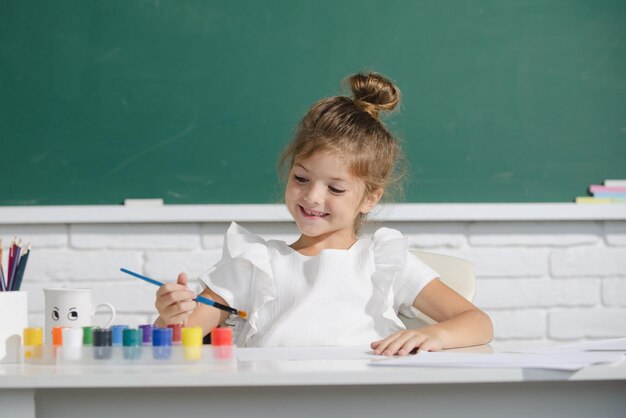 Kindermädchen in der Schule zeichnet mit Farben Kinderkünstler Kreativität süßes Schulmädchen, das in der Klasse bei s zeichnet