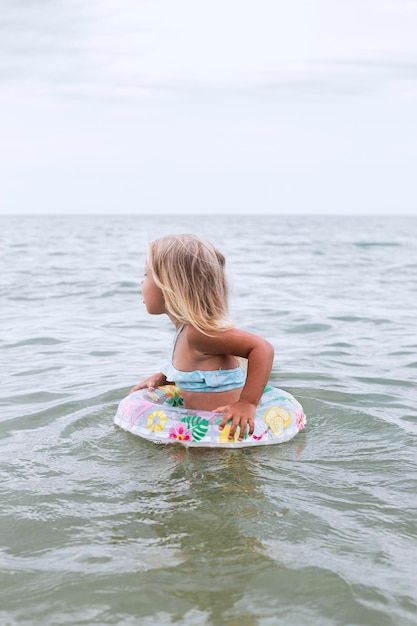 Kindermädchen in einem Badeanzug mit einem Kreis badet im Meer.