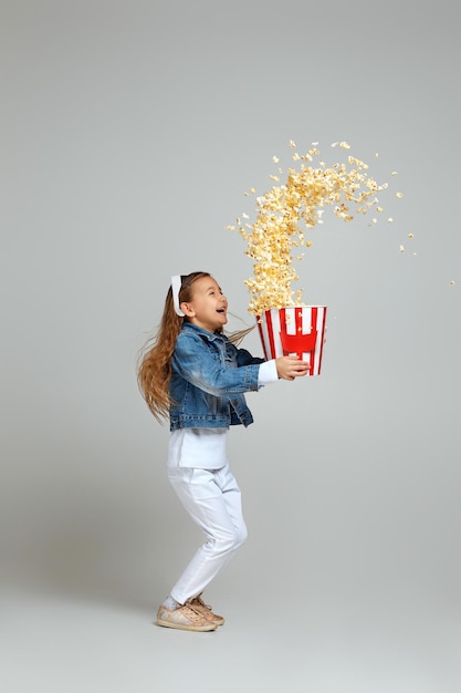 Kindermädchen in rotblauer d-Brille, die einen Eimer mit fliegendem Popcorn hält