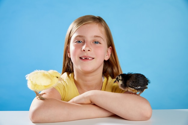 Kindermädchen mit den Küken, die auf Blau spielen