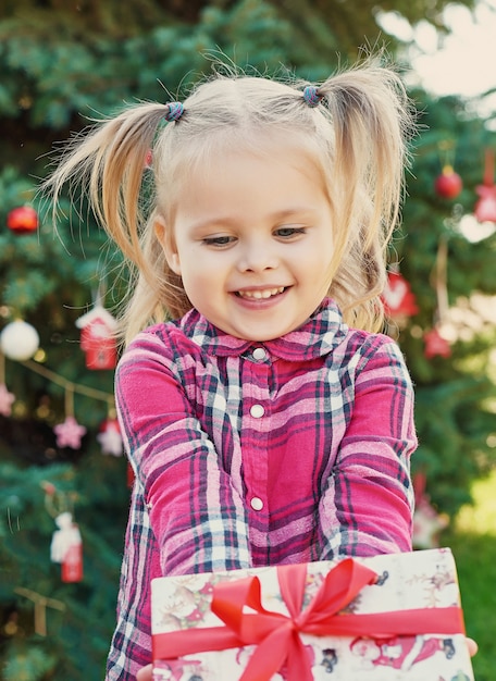 Kindermädchen mit Geschenken nahe einem Weihnachtsbaum, Weihnachten im Juli auf Natur