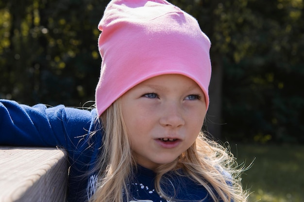 Kindermädchen mit Hut sitzt an einem Holztisch auf der Straße