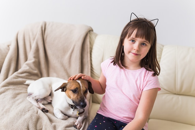 Kindermädchen mit niedlichem Hund Jack Russell Terrier auf der Couch.