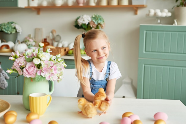 Kindermädchen mit Ostereiern und Hühnern in der Küche. Glückliches Osterkonzept. Glückliche Familie, die sich auf Ostern vorbereitet.