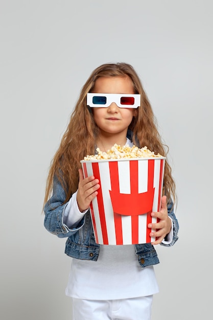 Kindermädchen mit rotblauer d-Brille, die Spaß haben und Popcorn-Eimer halten
