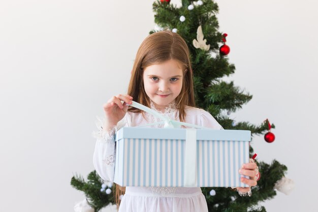 Kindermädchen öffnet Geschenkbox über Weihnachtsbaum