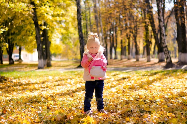 Kindermädchen schließt eine Rucksackschlange auf einem Hintergrund der Herbstlandschaft