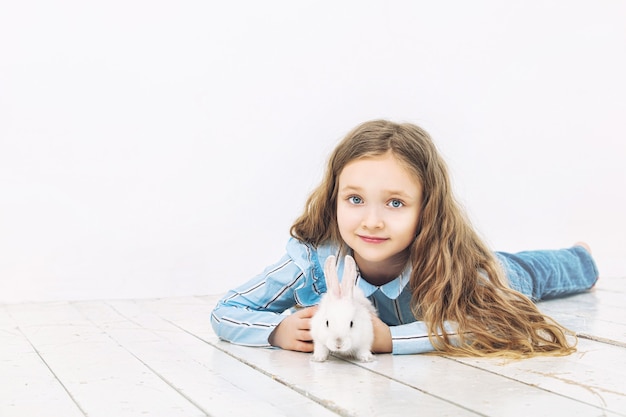 Kindermädchen schön nett fröhlich und glücklich mit kleinem Tierkaninchen auf weißem Wandhintergrund