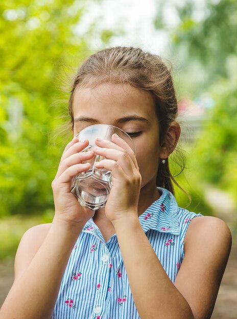 Foto kindermädchen trinkt wasser aus einem glas.