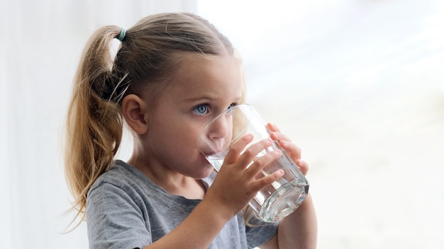 Kindermädchen trinkt Wasserschattenbildfensterhintergrund