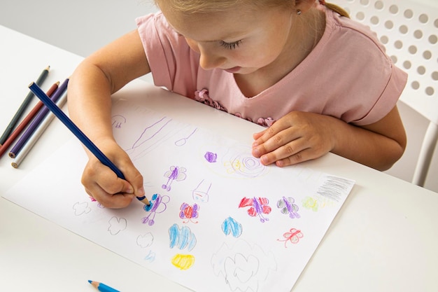 Kindermädchen zeichnet mit Buntstiften auf weißem Papier Draufsicht flach liegend