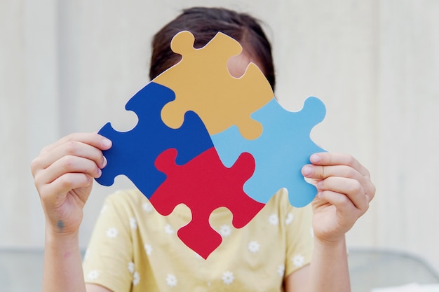 Kindermädchenhände halten Puzzle-Puzzle, Konzept der psychischen Gesundheit, Weltautismus-Bewusstseins-Tag