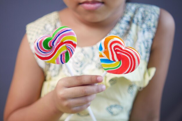 Kindermädchenhand halten Regenbogenherzformsüßigkeit