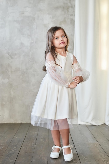 Kindermode. Kleines stilvolles Mädchen im weißen Kleid.