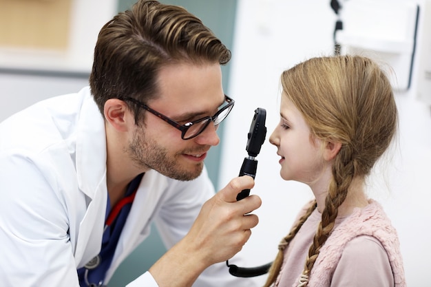 Kinderoptometrie männlicher Optiker Optiker Arzt untersucht das Sehvermögen des kleinen Mädchens