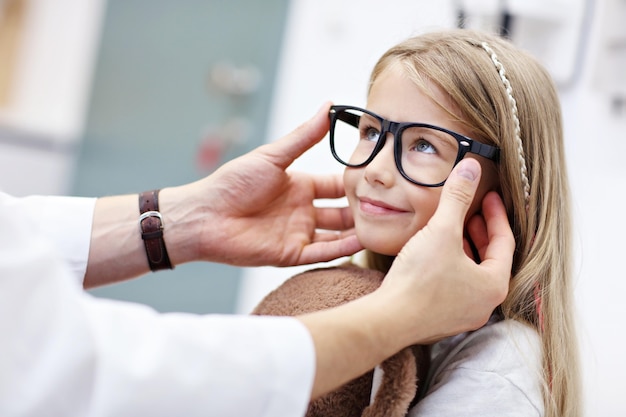 Kinderoptometrie männlicher Optiker Optiker Arzt untersucht das Sehvermögen des kleinen Mädchens