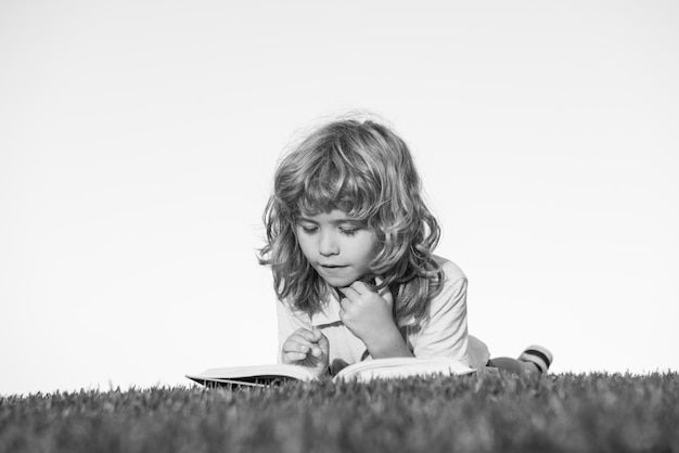 Kinderphantasie, Innovation und Inspiration Kinderporträt im Freien eines kleinen Jungen, der ein Buch liest
