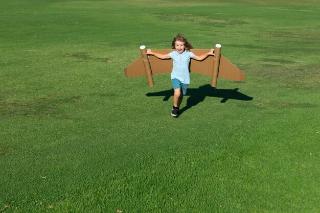 Kinderphantasie-Kinderpilot mit Papierflügeln, die Spaß an Sommerferien im Freien und Reisekonzept haben