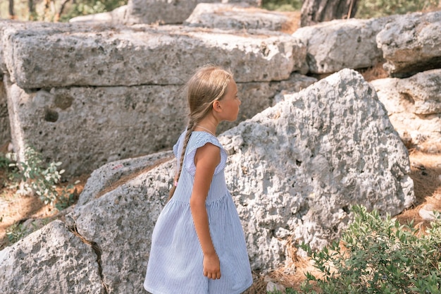 Kinderreisende im Alter von acht Jahren reisen und erkunden die antiken Ausgrabungen der Ruinen der antiken lykischen Stadt Phaselis in der Türkei während der Sommerferien in der Natur in den Bergen im Freien