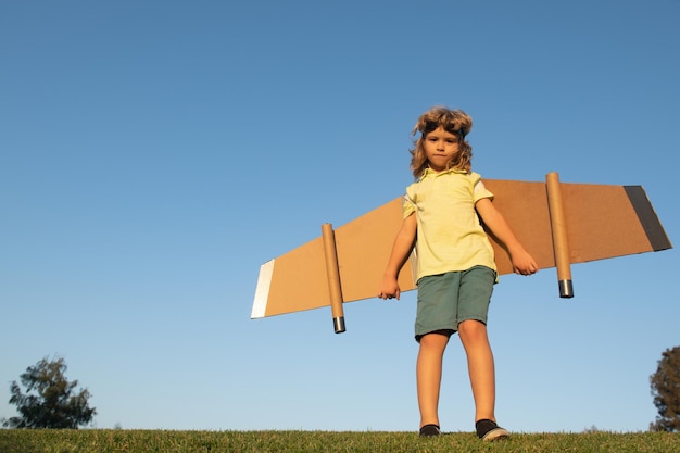 Kinderreisender mit Rucksackflügeln Kind spielt Pilotflieger und träumt draußen im Park glückliches Kind