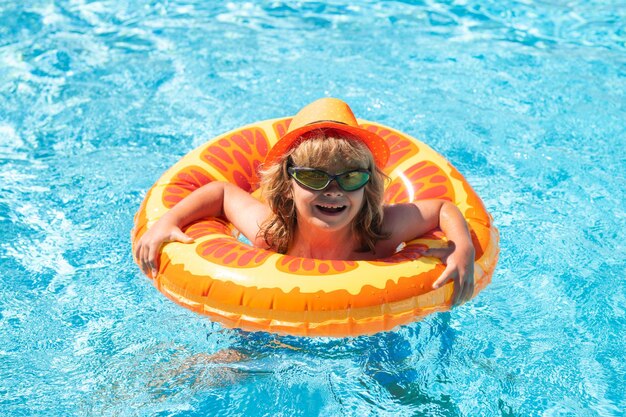 Kinderschwimmen im Pool spielen mit schwimmendem Ring lächelnd süßes Kind mit Sonnenbrille schwimmt mit aufblasbarem r