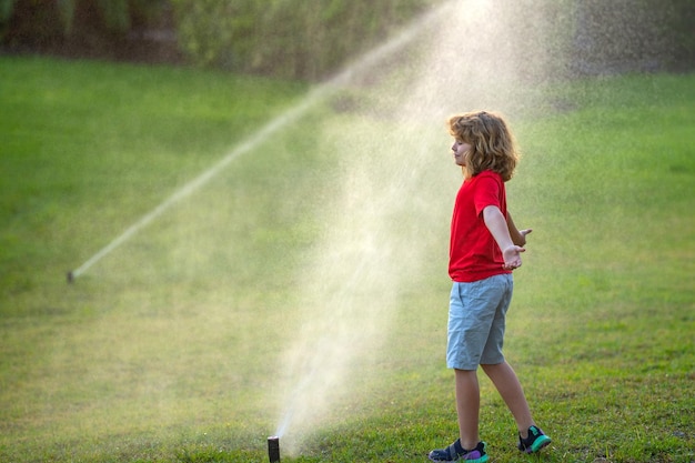 Kinderspiel im Sommergarten Grasbewässerung automatisches Sprinkler-Bewässerungssystem in einem grünen Park