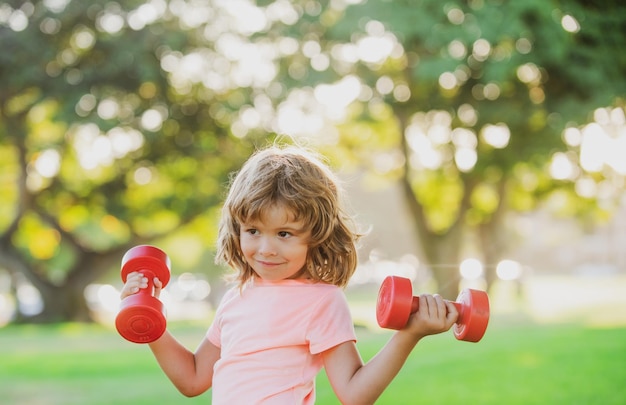 Kindersport. Junge, der im Park trainiert. Aktiver gesunder Lebensstil. Sportkind mit Hantel.