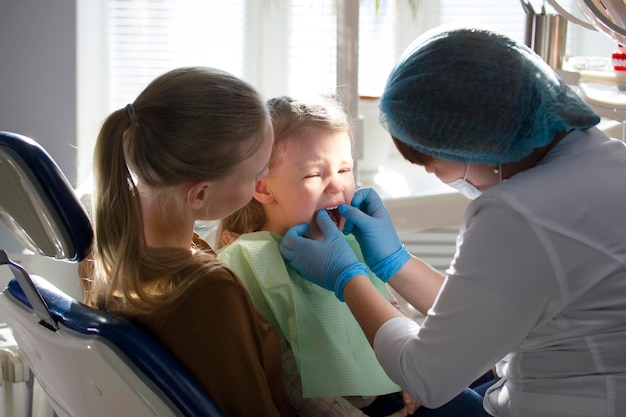 Kinderstomatologie - Zahnarzt und kleines Mädchen mit Mama, Nahaufnahme