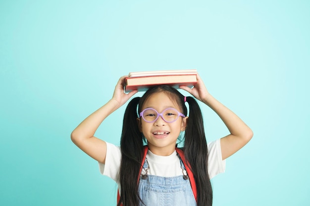 Kinderstudenten, die zur Schule gehen Mädchen lustige lächelnde Kinderstudenten Mädchen mit Brille halten Bücher auf dem Kopf