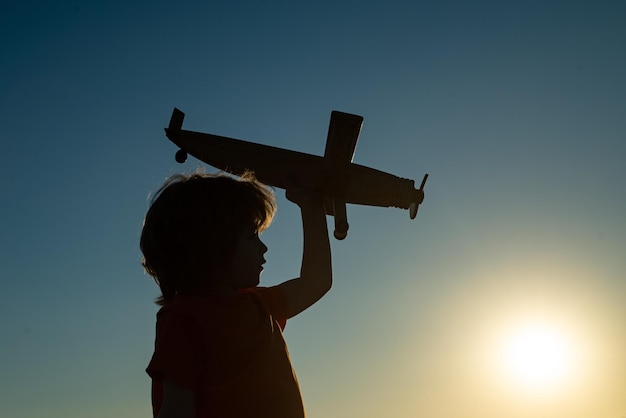 Kinderträume. Junge Pilot mit Spielzeugflugzeug, Silhouette. Kind, das draußen spielt. Glückliche Kindheit. Träumen.