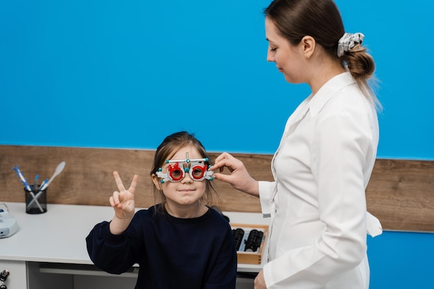 Kinderuntersuchung beim Kinderaugenarzt zur Auswahl eines Probebrillengestells zur Untersuchung des Sehsystems des Kindes. Der Augenarzt wählt Gläser für das Probebrillengestell aus