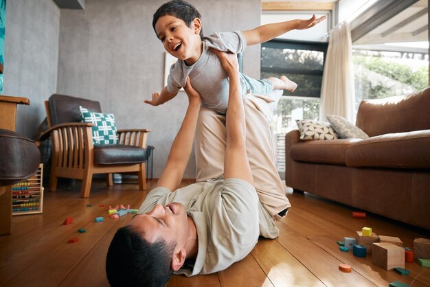 Foto kindervater und flugzeugspiele zu hause auf dem boden des wohnzimmers zur unterstützung, glückliches zusammensein und verrückten spaß. vaterjunge und aufgeregtes kind fliegen nach freiheit, fantasie und spielen mit ausgeglichenheit, sorgfalt und energie