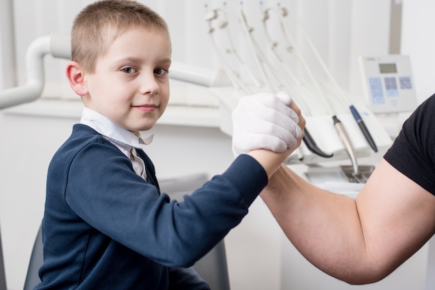 Kinderzahnarzt schüttelt dem Jungen in der Zahnarztpraxis die Hand