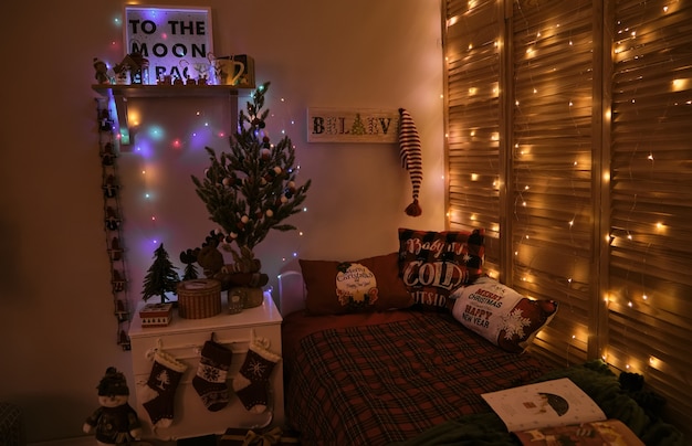 Kinderzimmer zu Weihnachten und Neujahr dekoriert, mit Bett und Lichtern, in klassischen rot-grünen Farben