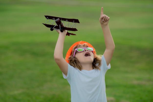 Kindheit auf dem Land Kid spielt mit Spielzeugflugzeug und träumt von der Zukunft Fröhlicher Junge Pilot spielt mit dem Flugzeug im Freien