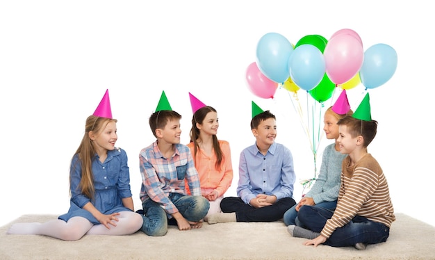 kindheit, ferien, freundschaft und personenkonzept - glücklich lächelnde kinder in partyhüten zum geburtstag